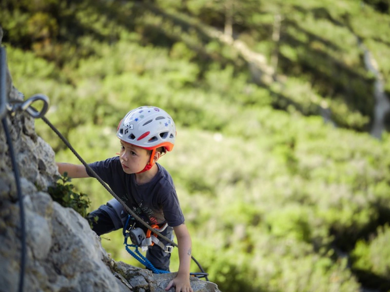 Enfant grimpant sur une paroi équipée lors d’une sortie Via Ferrata famille à Saint-Paul-de-Fenouillet dans les Pyrénées-Orientales.