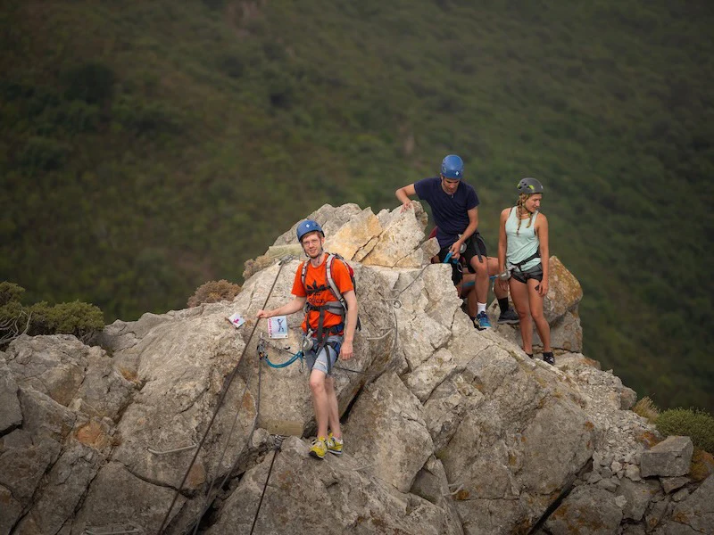 Participants faisant une pause sur une arête rocheuse lors de la Via Ferrata La Panoramique à Saint-Paul-de-Fenouillet.