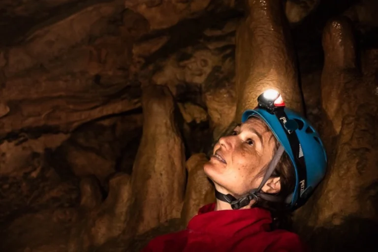 Spéléologue observant des concrétions dans une grotte lors d’une sortie spéléologie dans les Pyrénées-Orientales