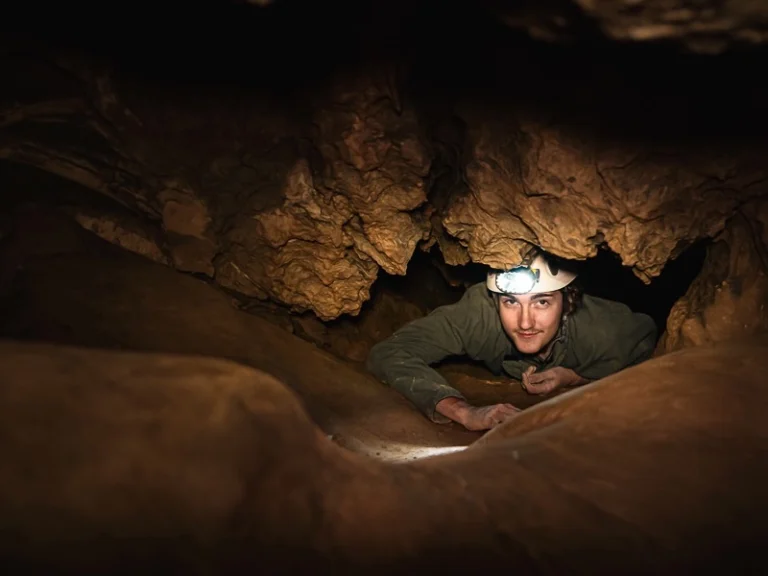 Spéléologue progressant dans un passage étroit lors d’une sortie spéléologie dans les grottes de Galamus