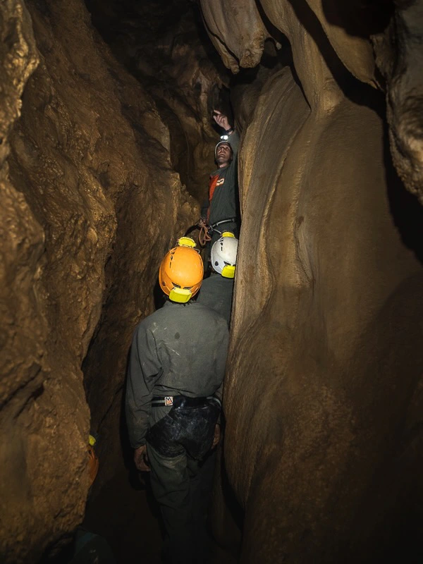Spéléologues progressant dans une étroiture lors d’une sortie spéléologie dans les grottes de Galamus