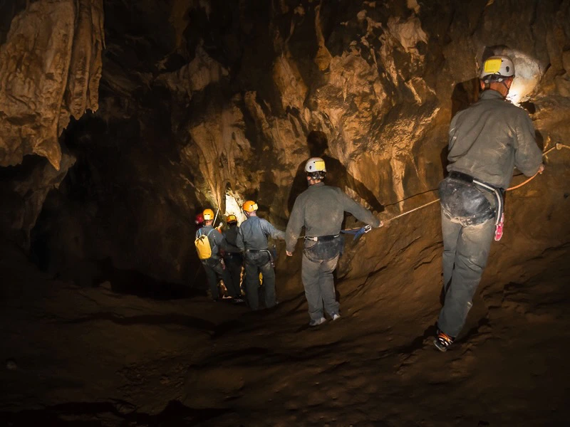 Groupe progressant dans une grande galerie lors d’une sortie spéléologie dans les grottes de Galamus