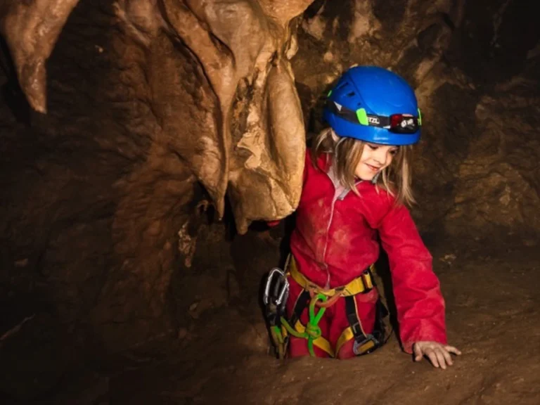 Enfant explorant un passage étroit dans une grotte lors d’une sortie spéléologie à Galamus dans les Pyrénées-Orientales