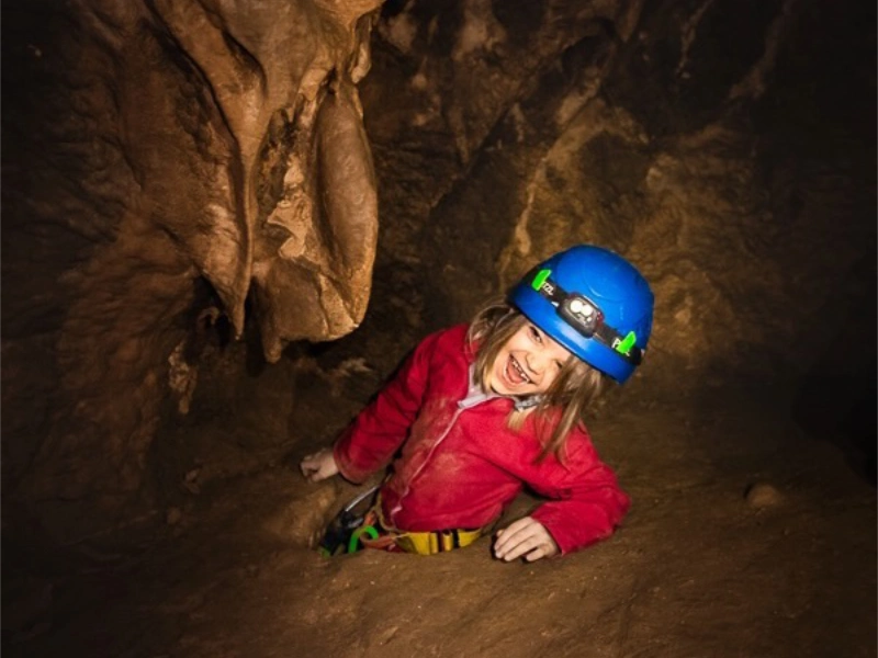 Enfant explorant un passage étroit dans une grotte lors d’une sortie spéléologie à Galamus dans les Pyrénées-Orientales