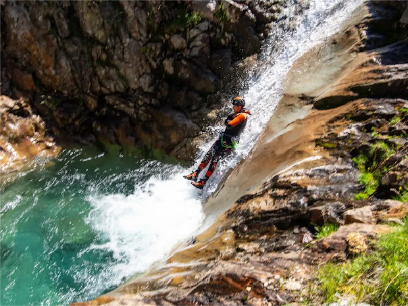 Participant glissant dans un toboggan naturel de cascade dans le canyon de l’Artigue en Ariège dans la vallée de Vicdessos