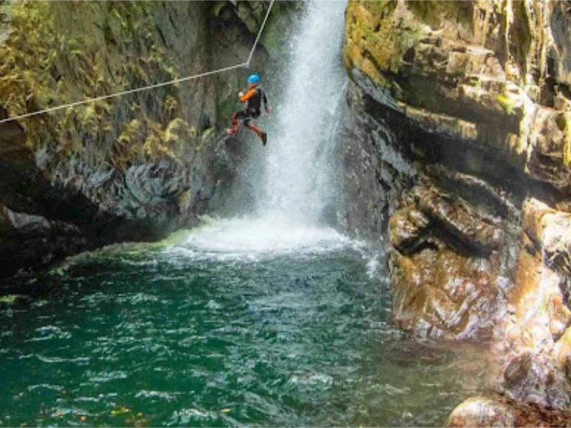 Participant en tyrolienne au-dessus d’une cascade dans le canyon de Marc, vallée de Vicdessos en Ariège dans les Pyrénées