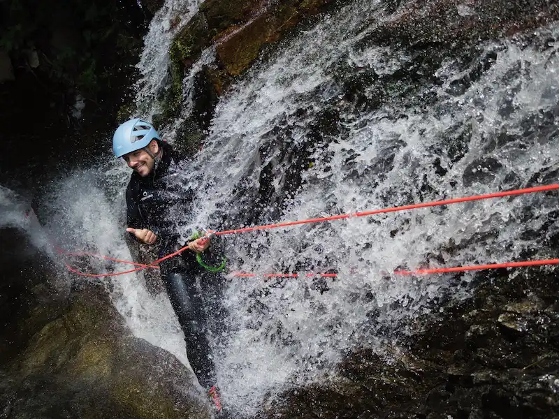 Pratiquant en descente en rappel sous une cascade dans le canyon du Baousous à Céret dans les Pyrénées-Orientales