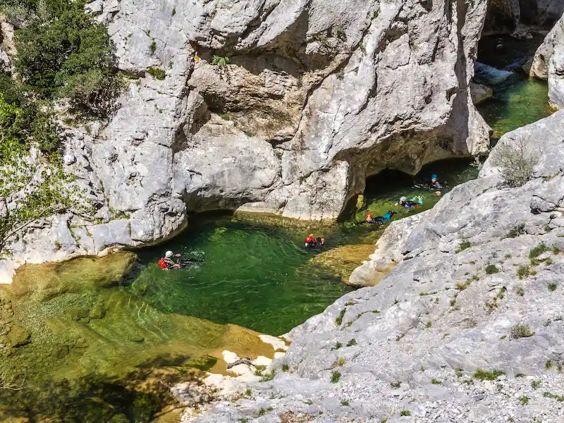 Participants nageant dans une vasque d’eau turquoise lors d’une sortie canyoning dans le canyon de Galamus dans les Pyrénées-Orientales