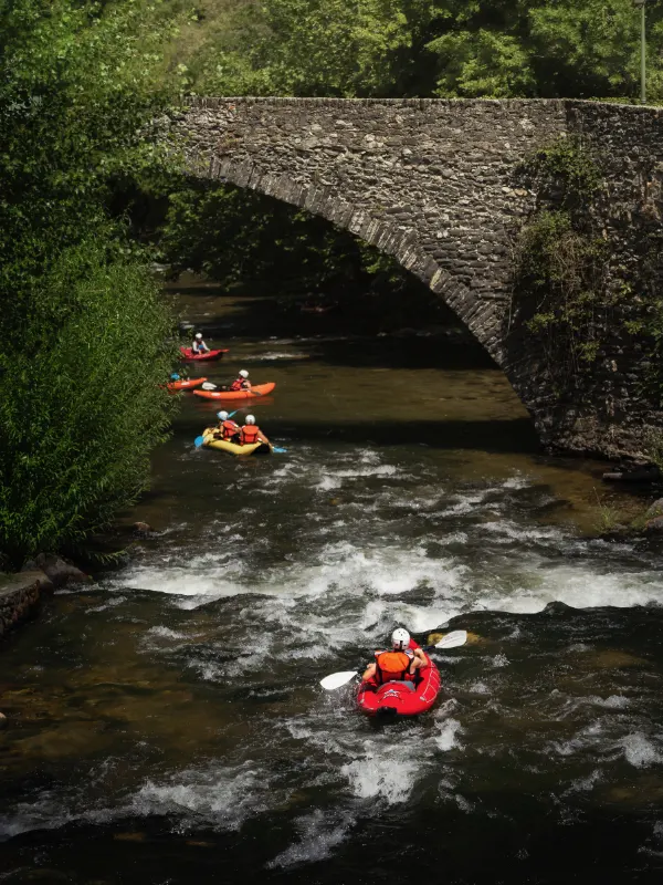 groupe pratiquant le canoraft sur la rivière Aude sous un pont en pierre près d’Axat dans les Pyrénées audoises