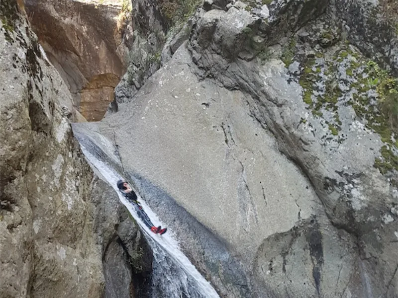 Participant descendant un grand toboggan naturel dans le canyon du Llech lors d’une sortie de canyoning dans les Pyrénées-Orientales près de Prades