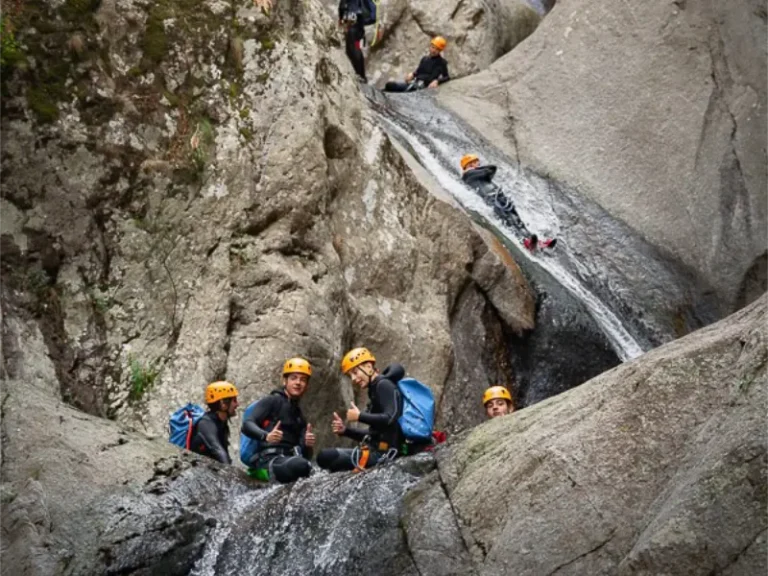 Groupe de participants descendant un toboggan naturel dans le canyon du Llech lors d’une sortie de canyoning dans les Pyrénées-Orientales