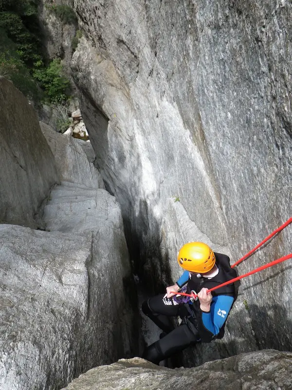 Participant descendant en rappel dans la faille étroite du canyon du Mas Calsan lors d’une sortie canyoning près de Céret dans les Pyrénées-Orientales.