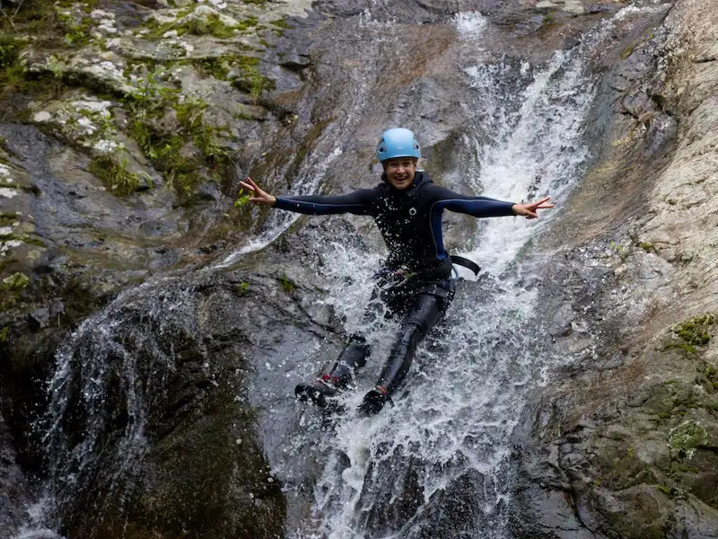 Pratiquante descendant un toboggan naturel sous une cascade dans le canyon du Baousous à Céret dans les Pyrénées-Orientales