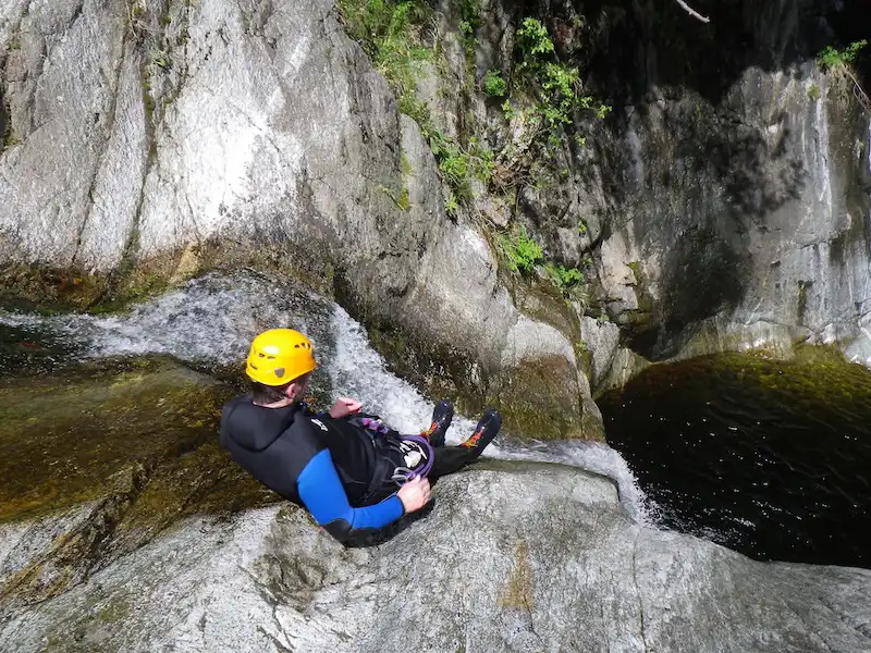 Participant s’engageant dans un toboggan naturel se terminant dans une vasque lors d’une sortie canyoning dans le canyon du Mas Calsan près de Céret dans les Pyrénées-Orientales.